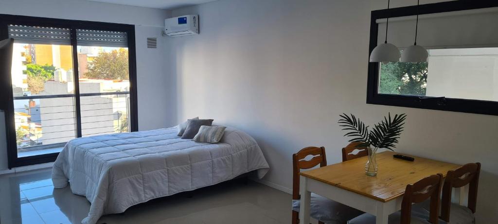 um quarto com uma cama, uma mesa e uma janela em Francia Uno em Rosário