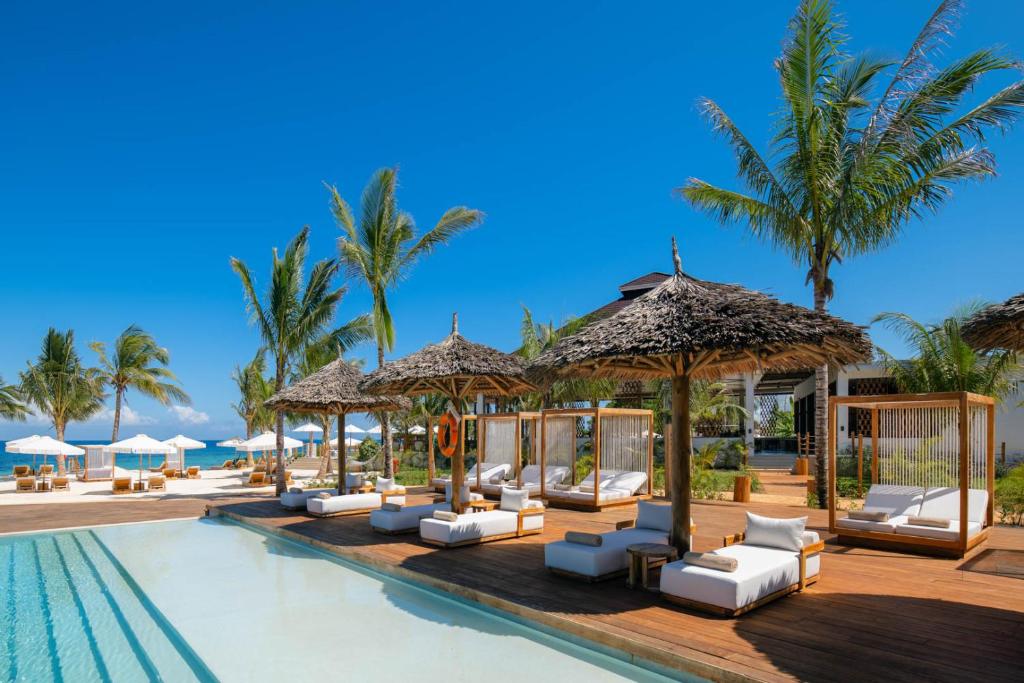 a pool at a resort with lounge chairs and umbrellas at Aldiana Club Zanzibar Kwanza in Kizimkazi