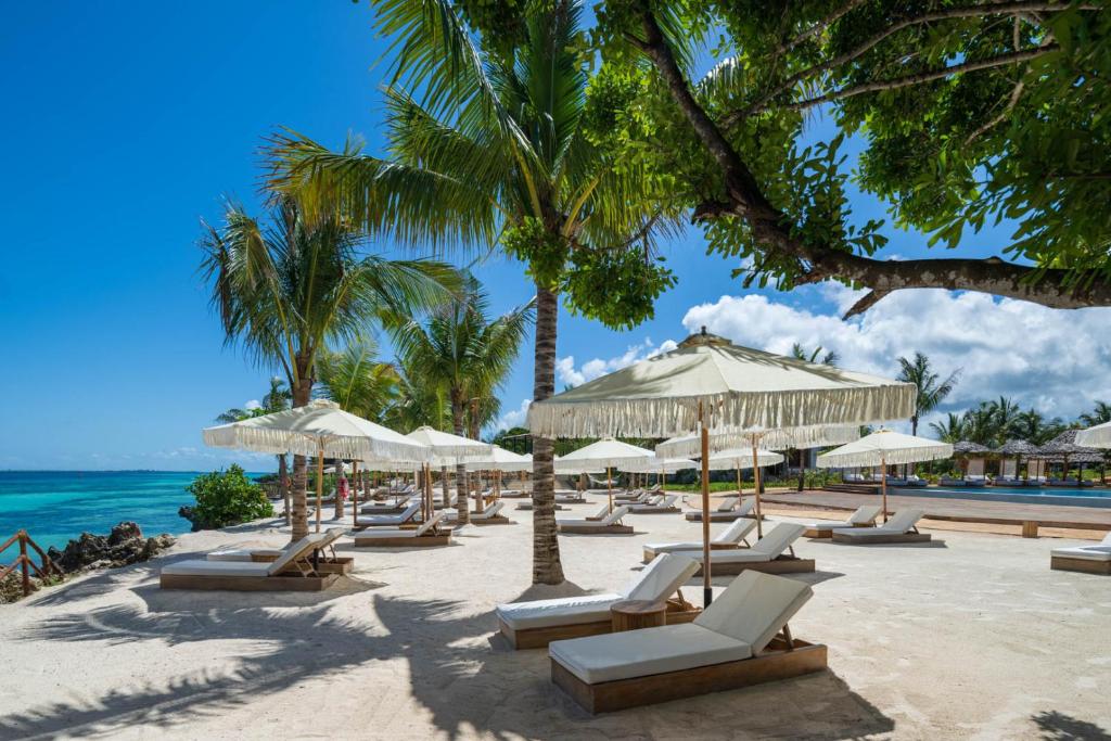 a beach with chairs and umbrellas and the ocean at Aldiana Club Zanzibar Kwanza in Kizimkazi