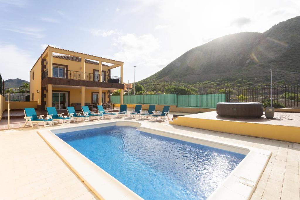 a house with a swimming pool and chairs and a building at Villa esclusiva a 1 chilometro da Playa de Los Cristianos in Los Cristianos