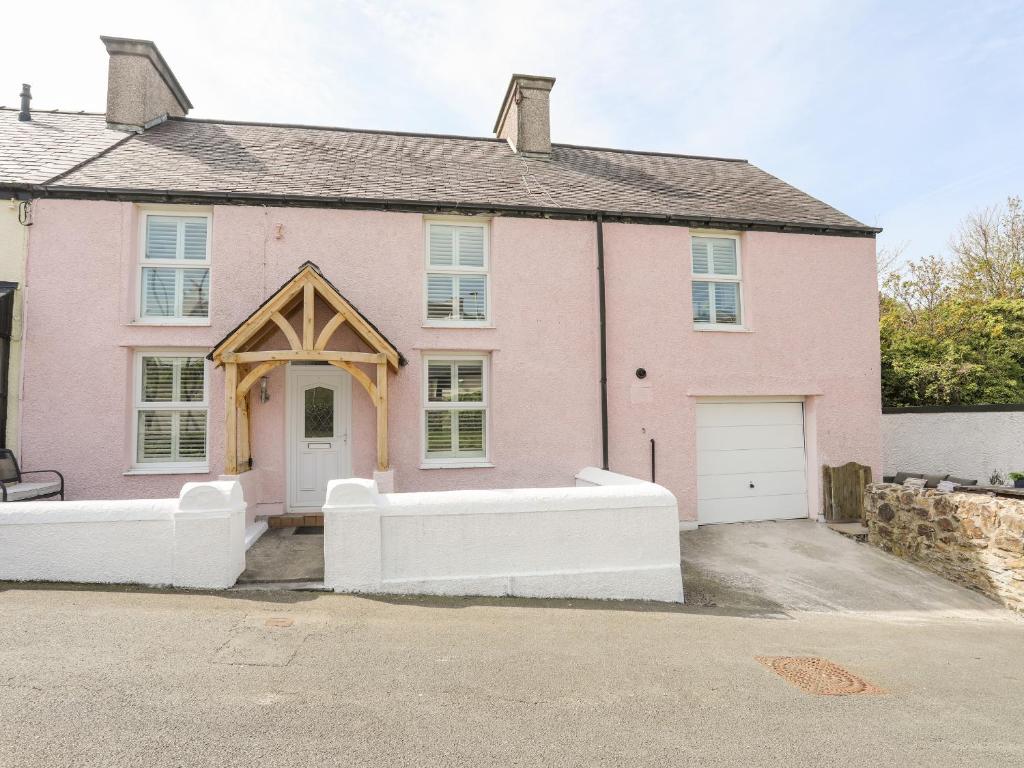 a pink house with a white fence in front of it at 13 Quay Street in Amlwch
