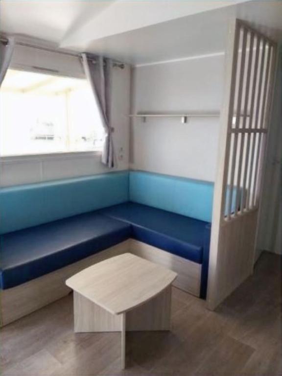 Zimmer mit einer blauen Bank und einem Tisch in der Unterkunft Mobil Home (Clim, Tv)- Camping Narbonne-Plage 4* - 020 in Narbonne-Plage