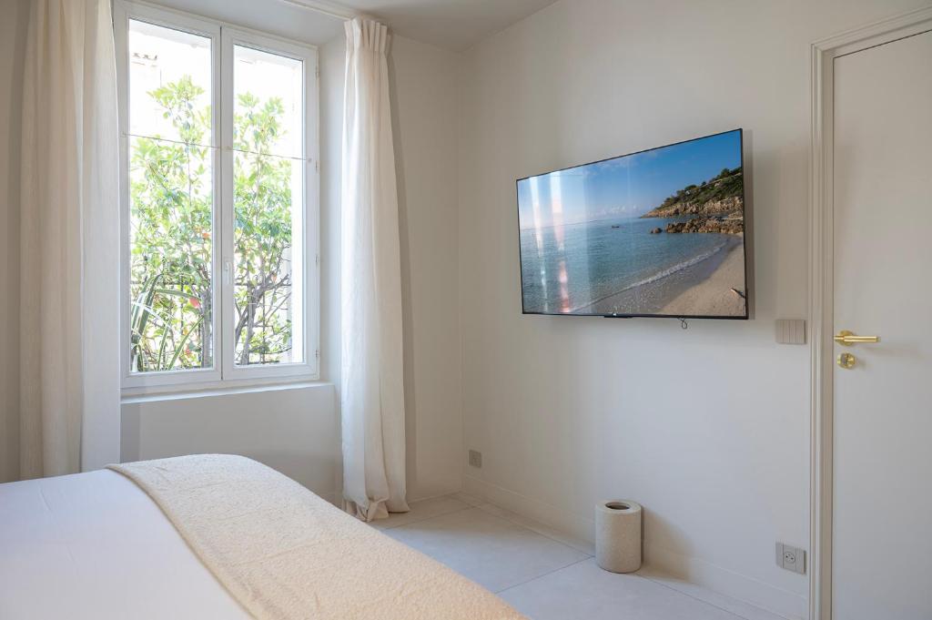 a white bedroom with a television on a wall at Lou Cagnard in Saint-Tropez