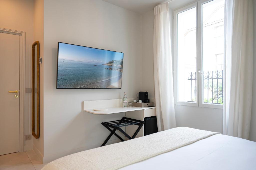 a bedroom with a bed and a desk and a tv on the wall at Lou Cagnard in Saint-Tropez