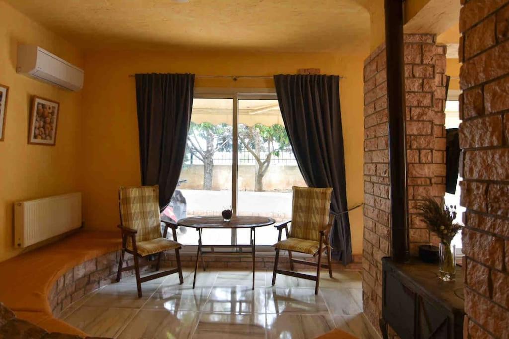sala de estar con mesa, sillas y ventana en Agia Marina apartment, en Aghia Marina