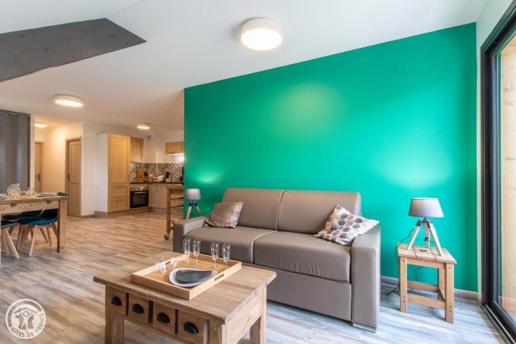 een woonkamer met een bank en een groene muur bij Gite Annecy 201- Au Royaume des Castors - Appt 201 in Doussard