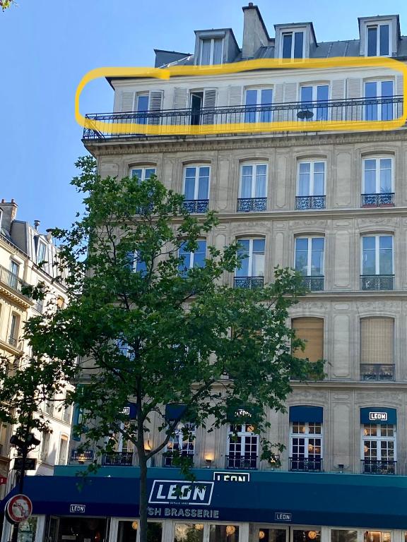 un grand bâtiment avec un arbre devant lui dans l'établissement Bel appartement Montparnasse 70m2, à Paris