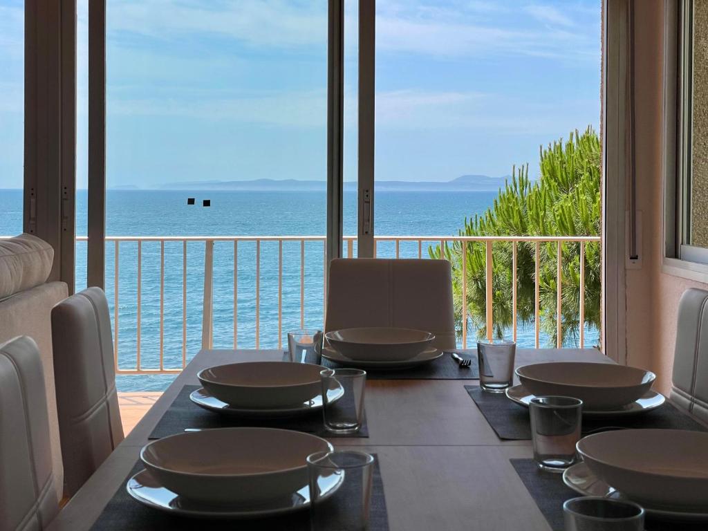 uma mesa de jantar com vista para o oceano em Luminoso apartamento frente al mar con piscina em Roses