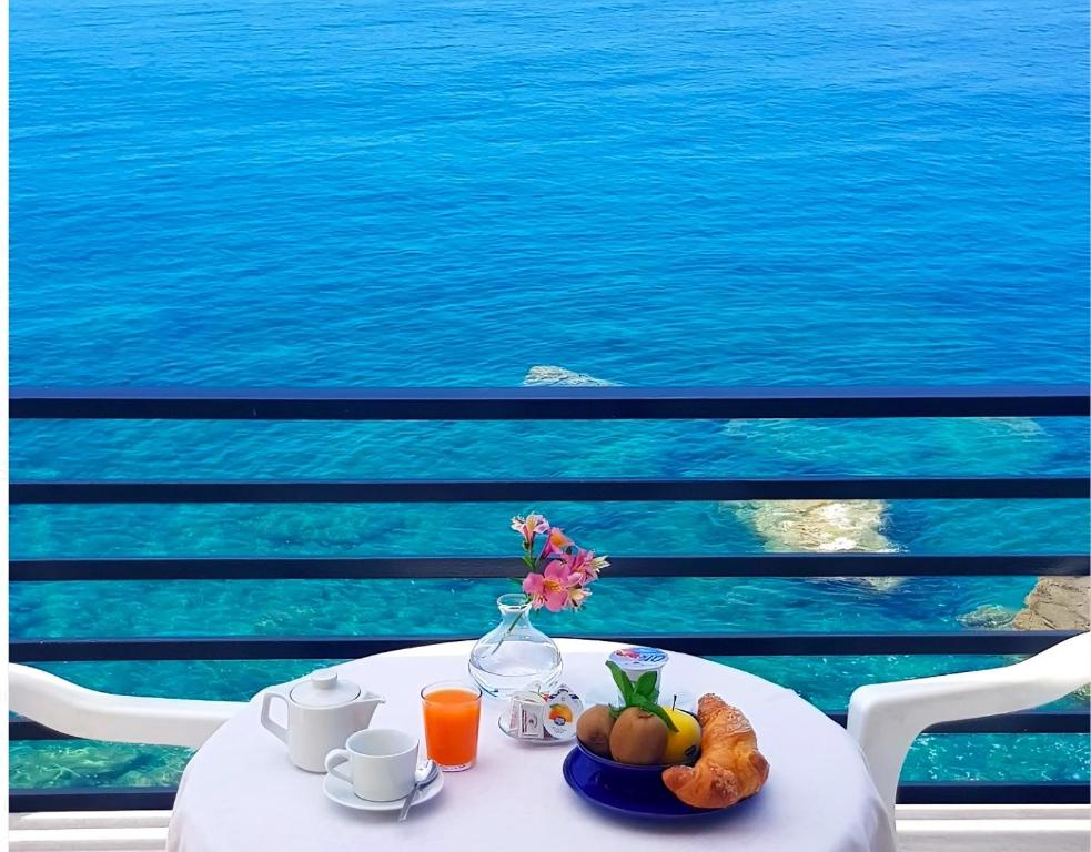 een witte tafel met een fruitschaal en een vaas met bloemen bij Hotel La Scogliera in Cavi di Lavagna