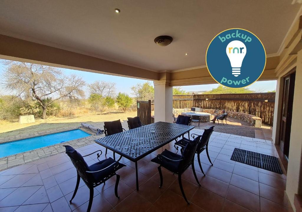 a patio with a table and chairs and a swimming pool at Zebula No 2 Waterbergs Over the Savannah 4 Bedroom in Mabula