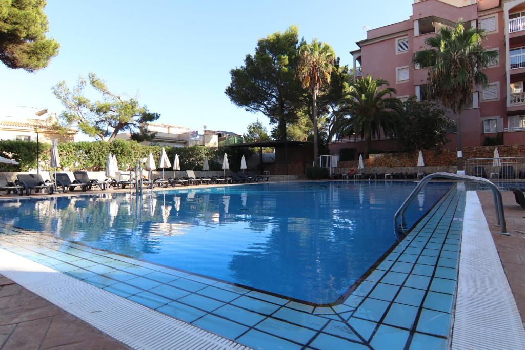 a large swimming pool with chairs and a building at Apartamentos Sol Radiante in Canyamel
