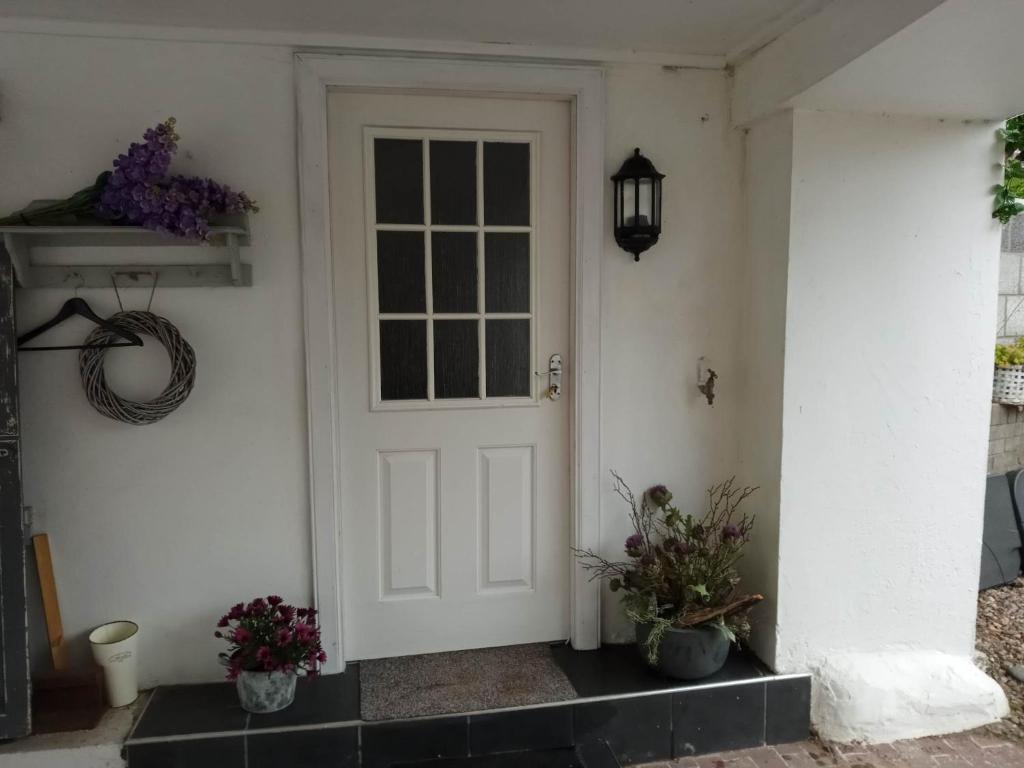 a white door of a house with two potted plants at Lovely Wee House in Lundin Links perfect beaches in Lundin Links