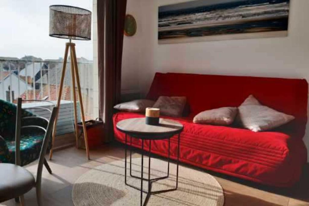 un salon avec un canapé rouge et une table dans l'établissement Bright apartment near the sea, à Le Touquet-Paris-Plage