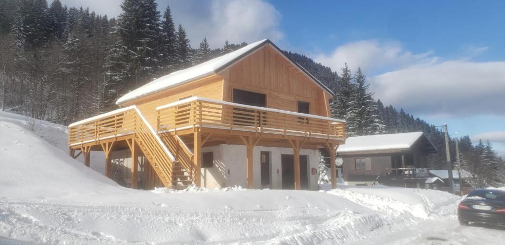 una cabaña en la nieve con un coche aparcado delante en Chalet le Lys Martagon en Saint-Pierre-dʼEntremont