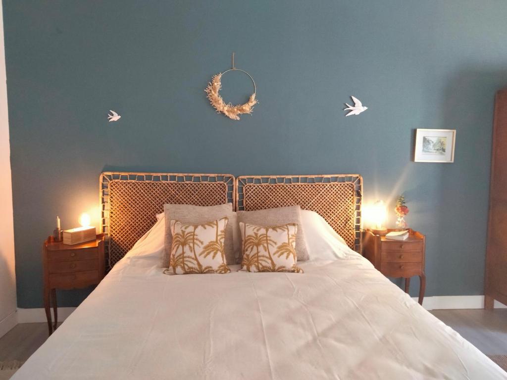 - un lit avec deux oreillers et un mur bleu dans l'établissement La Bergeronnette, à Montreuil-Bellay