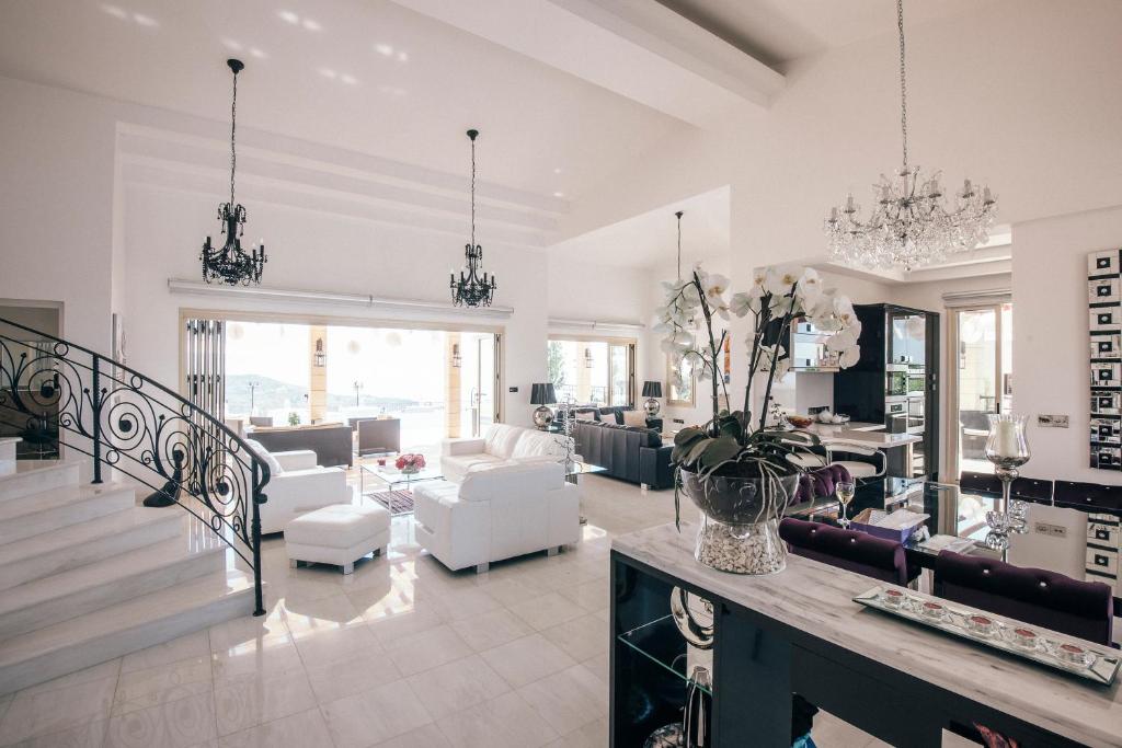una sala de estar con muebles blancos y una escalera. en Eagles Cliff Villa en Kathikas
