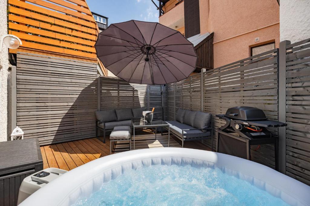 - un bain à remous sur une terrasse avec un parasol dans l'établissement Terrace apartment with 5 rooms, Whirlpool and BBQ, à Augsbourg