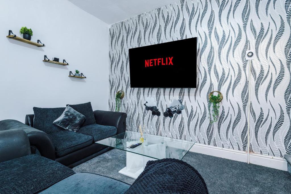 65 inch TV in Modern 2 Bed Hideaway في برادفورد: غرفة معيشة مع أريكة وطاولة