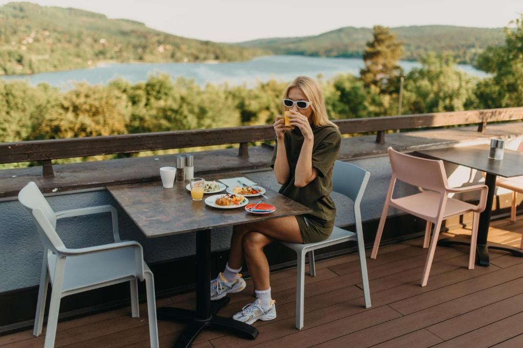 a woman sitting at a table eating food on a deck at OREA Resort Santon Brno in Brno