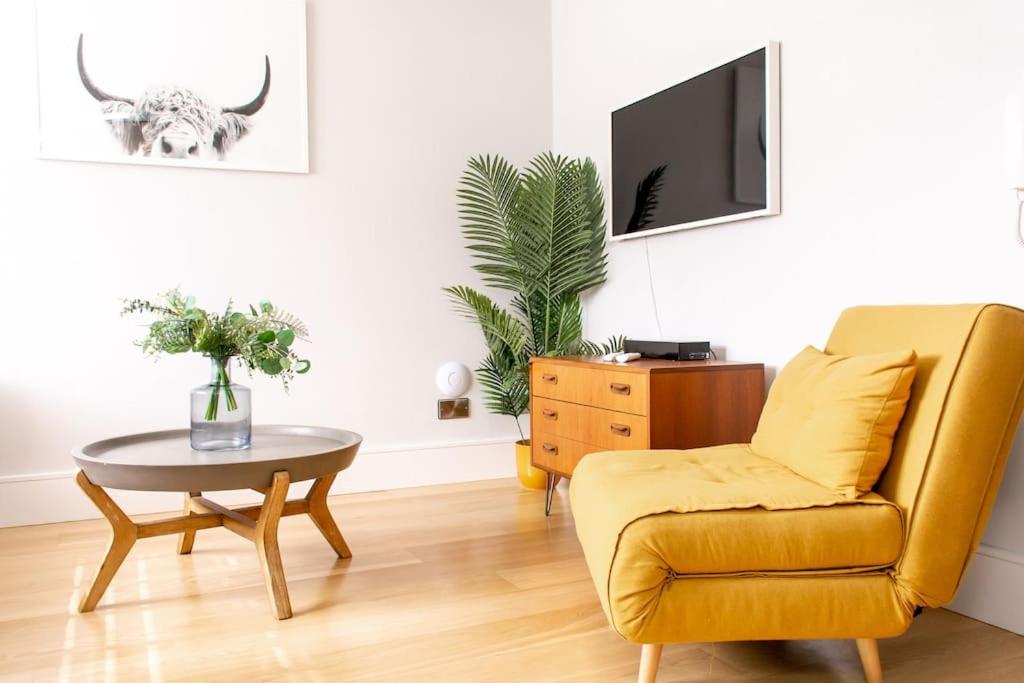 a living room with a yellow chair and a table at Hyper-central Newquay, sleeps 3 in Newquay