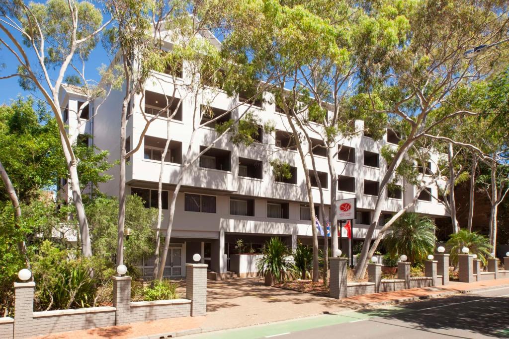 un edificio blanco con árboles delante de él en Metro Aspire Hotel Sydney, en Sídney