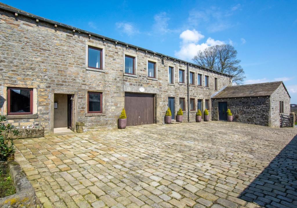 an old stone building with a brick driveway at Weavers Cottage in Cowling