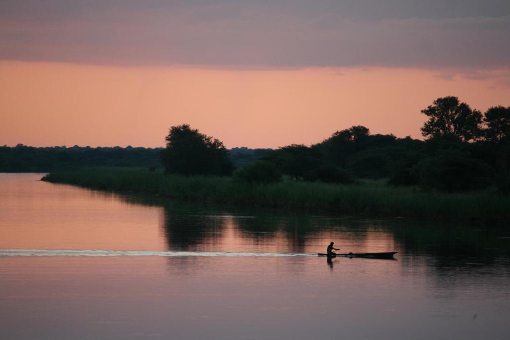 a person in a boat in the water at sunset at Mpora River Lodge in Rundu