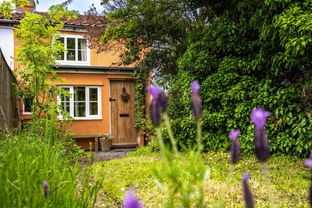 a garden with purple flowers in front of a house at 2 Fox Cottages in Darsham