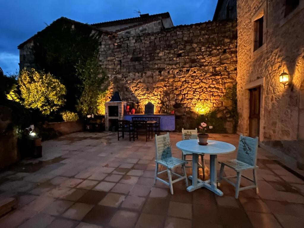 um pátio com uma mesa e cadeiras em frente a um edifício em Casa Rural La Ferrería em Vinuesa