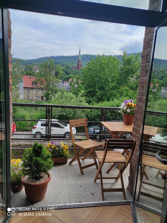 a balcony with a table and chairs and a view at Dawna Mleczarnia Apartament LOFT in Nowa Ruda