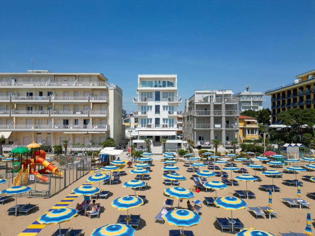 una spiaggia con un mucchio di sedie e ombrelloni di Hotel Boston 3 Stelle Superior Frontemare a Lido di Jesolo