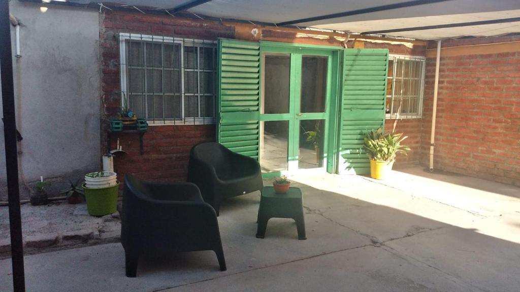 eine Terrasse mit 2 Stühlen und einer grünen Tür in der Unterkunft Picunches 4 in Neuquén