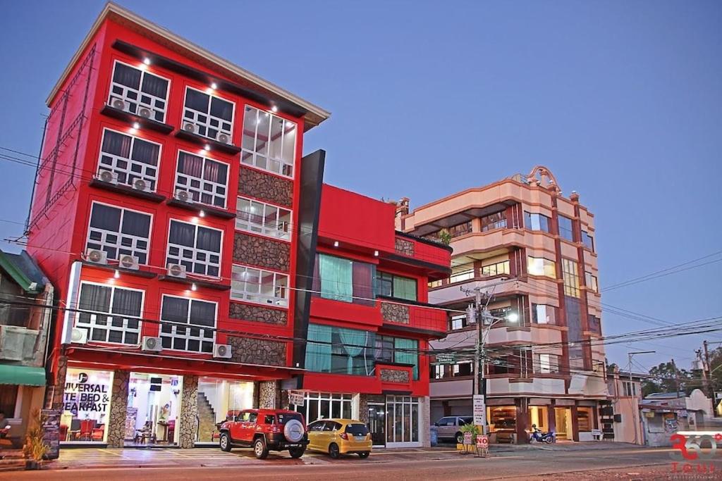 um edifício vermelho com carros estacionados em frente em Sabel Travelers Inn em Laoag