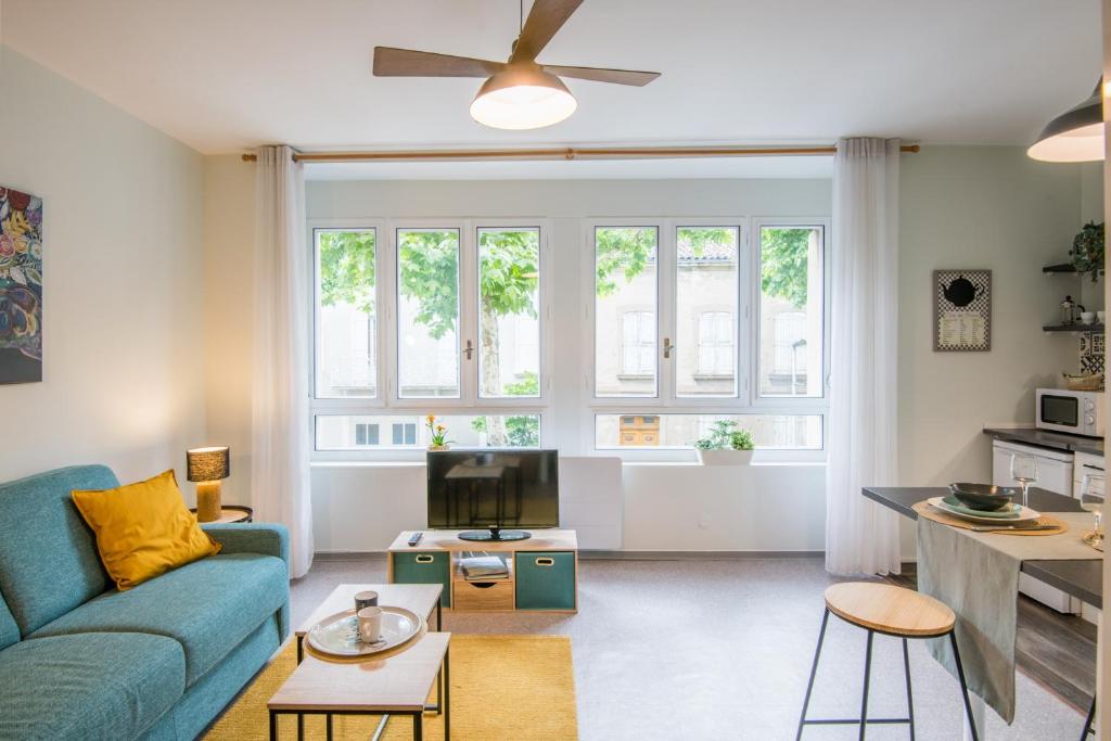 een woonkamer met een blauwe bank en een tv bij Cardabelle - Joli appt pour 2 avec parking privé in Millau