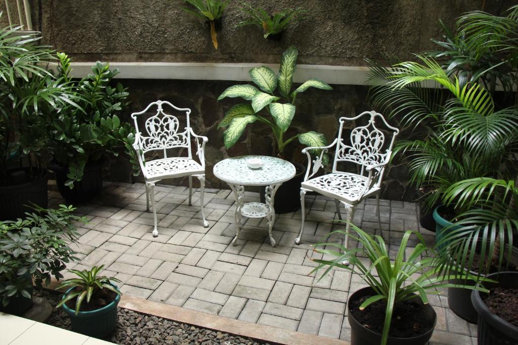a patio with two chairs and a table and some plants at Bed and Breakfast Tomang in Jakarta