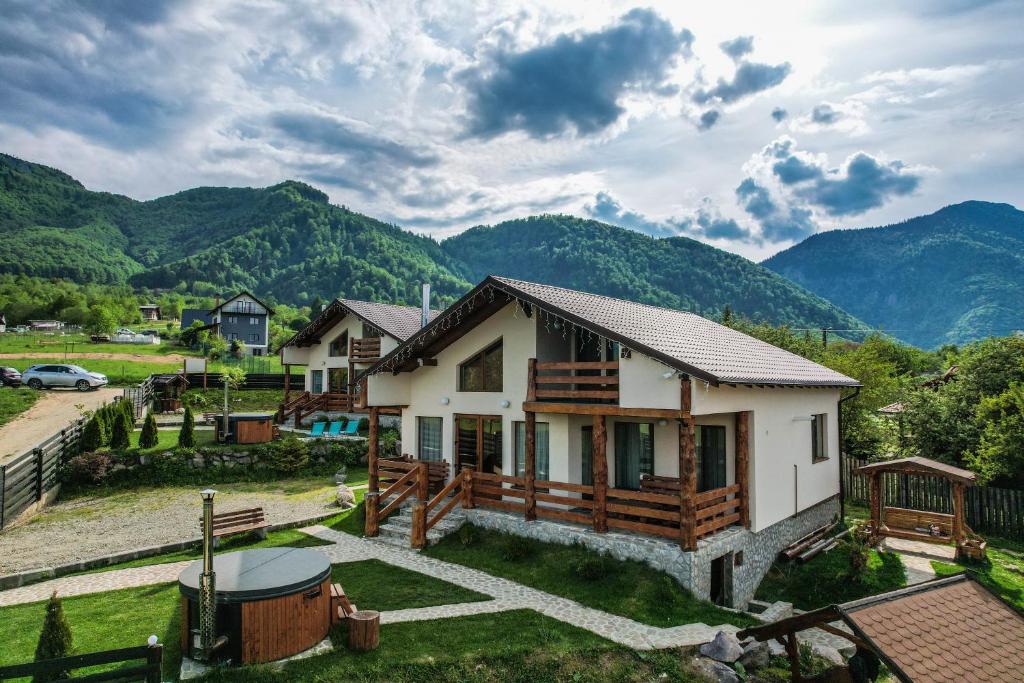uma casa com montanhas ao fundo em Green Hill Resort em Zarnesti
