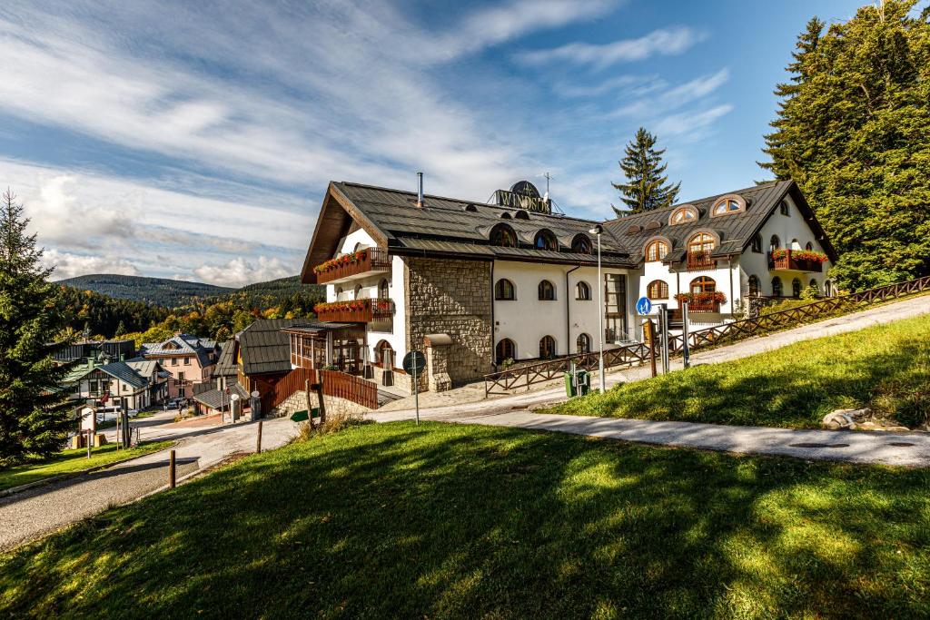 a large house on a hill with a green lawn at Wellness Hotel Windsor in Špindlerův Mlýn