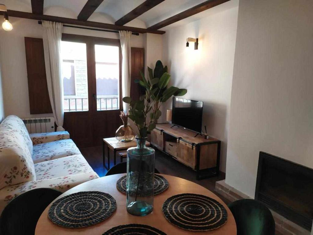 uma sala de estar com uma mesa e uma televisão em Apartamentos casa memé em Mora de Rubielos