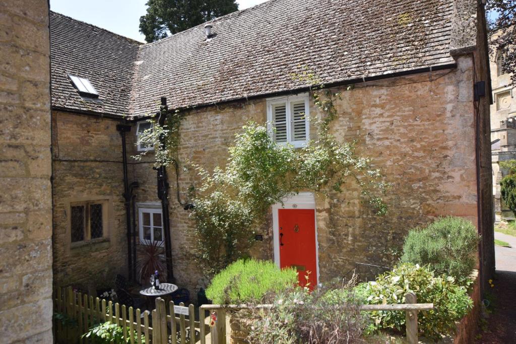 an old brick house with a red door at Church Cottage in Chipping Norton
