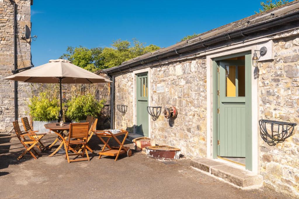 Cabaña de piedra con mesa, sillas y sombrilla en The Manor Stables at Moyglare Manor en Maynooth