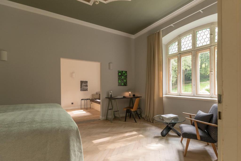 a bedroom with a bed and a desk and a window at Blyb Hotel in Gmund am Tegernsee
