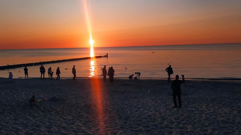 a group of people on the beach at sunset at Kolorowa Chata in Ustronie Morskie