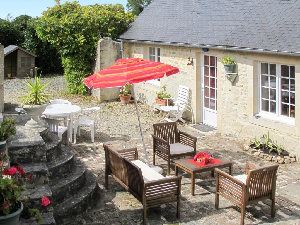 eine Terrasse mit einem Tisch, Stühlen und einem Sonnenschirm in der Unterkunft Holiday Home Les Lutins - COM400 by Interhome in Commes