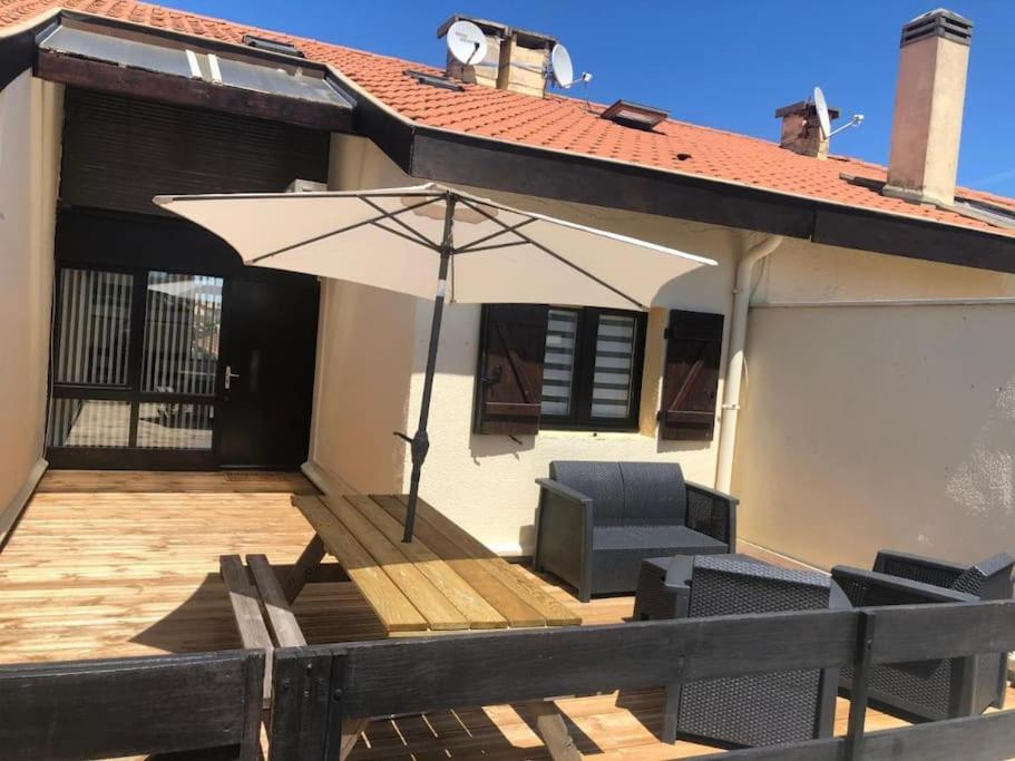 un patio avec un parasol et des chaises sur une terrasse dans l'établissement Lovely duplex - 50m fr. the sea, à Lacanau-Océan
