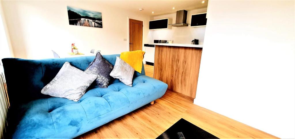 eine blaue Couch mit Kissen in einem Wohnzimmer in der Unterkunft Cliftonville Heights - 2 bed Home away from Home in Northampton