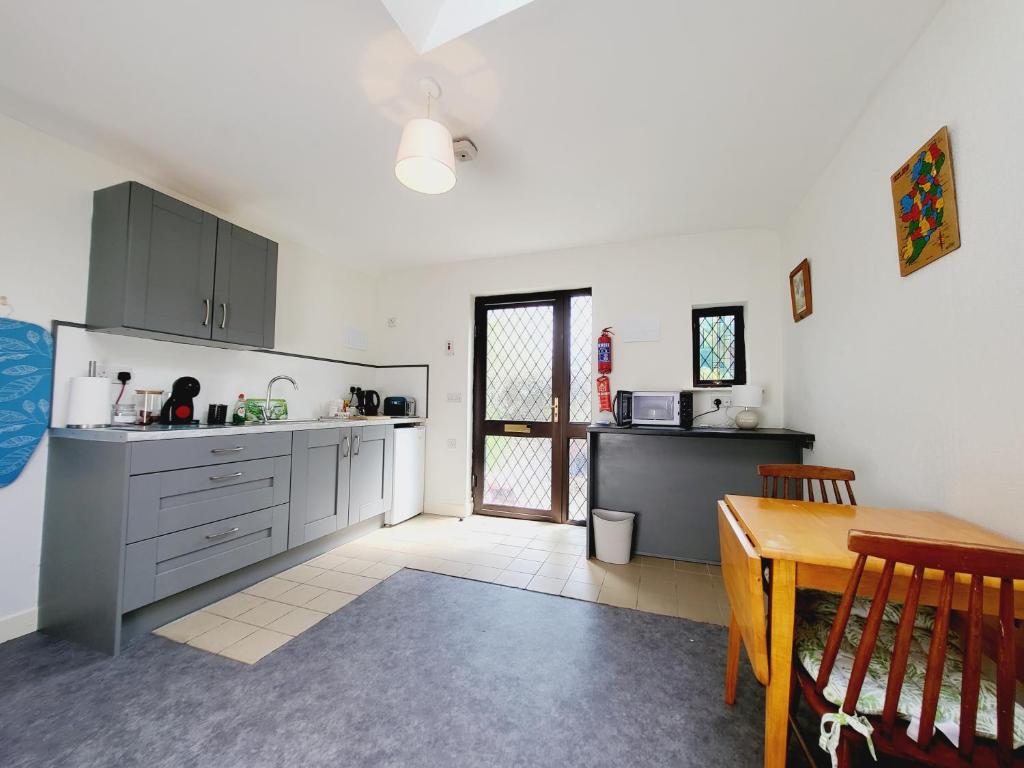 a kitchen with gray cabinets and a table in it at Oak Cottage 3 km from Rock of Cashel in Cashel