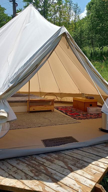 a canvas tent with a wooden table in a field at Glamping in the apuseni mountains in Grohoţele
