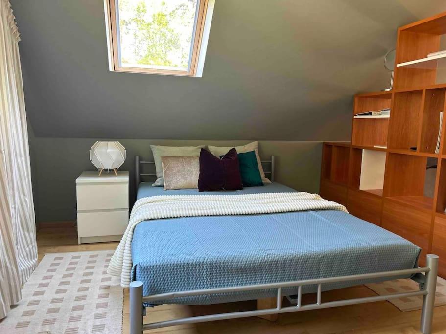 1 dormitorio con cama con sábanas azules y ventana en House in Pine forest Asari, en Jūrmala