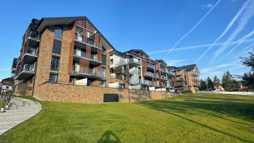 a large brick building with a green lawn in front of it at Lipno A1 in Lipno nad Vltavou