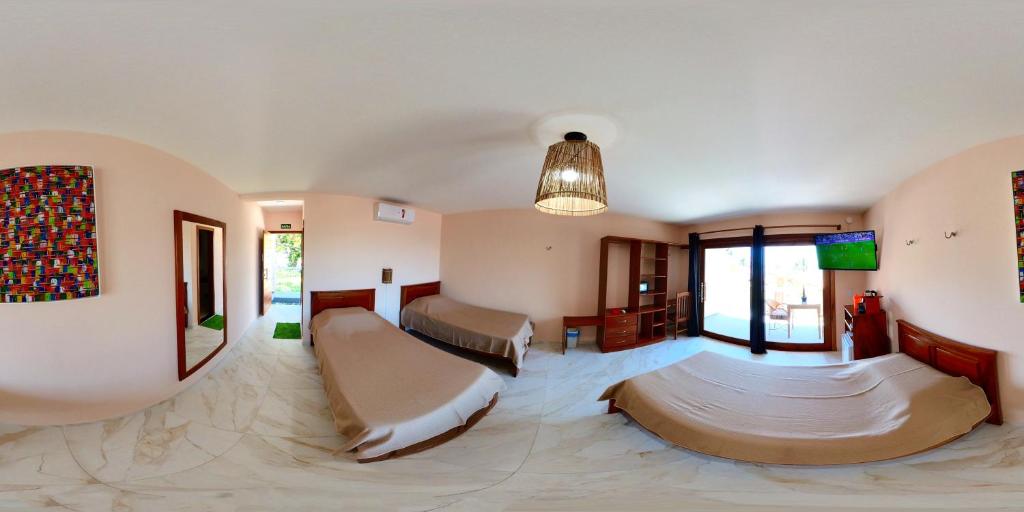 Cette grande chambre comprend 2 lits et une télévision. dans l'établissement De Olho no Mar A única pousada de frente para o mar em Paracuru, à Paracuru